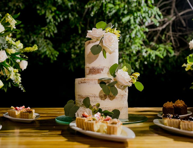 Mesa de postres de boda con pastel blanco de flores frescas y dulces gourmet